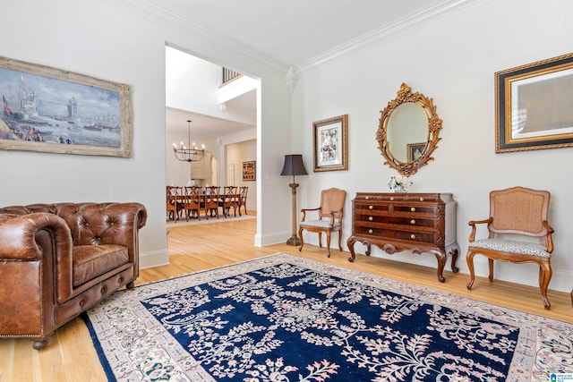 sitting room with a notable chandelier, crown molding, baseboards, and wood finished floors