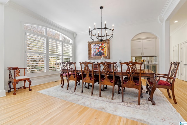 dining area featuring a chandelier, arched walkways, light wood finished floors, and ornamental molding