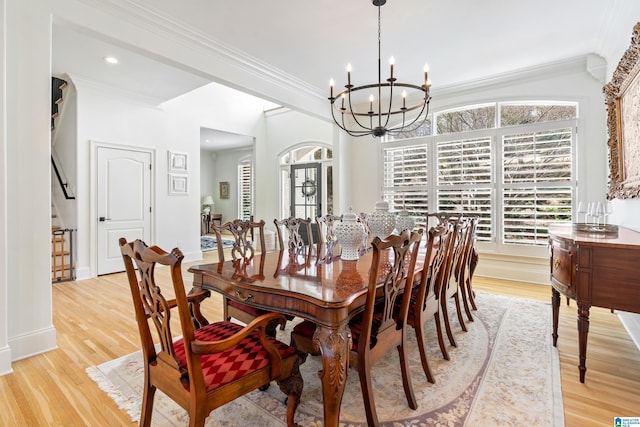 dining area with an inviting chandelier, crown molding, light wood-style flooring, and a wealth of natural light