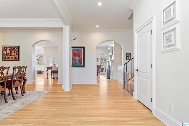 foyer entrance featuring baseboards, recessed lighting, arched walkways, ornamental molding, and light wood-type flooring