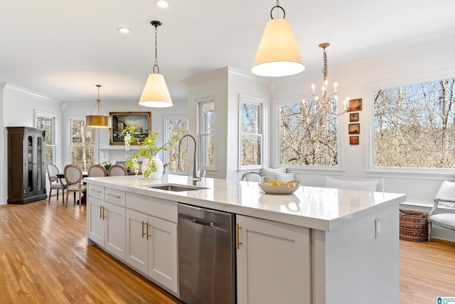 kitchen with light wood-style flooring, a sink, stainless steel dishwasher, crown molding, and light countertops