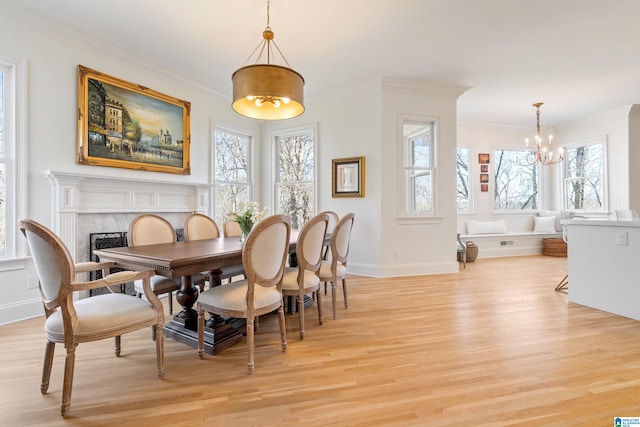 dining room featuring crown molding, light wood-style flooring, and a fireplace