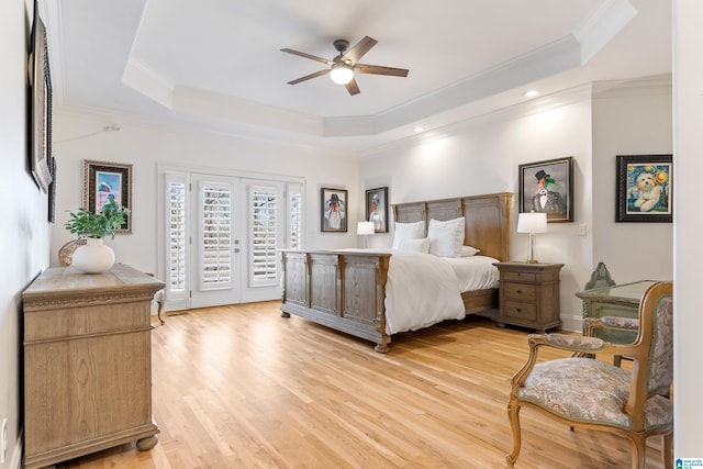 bedroom featuring a tray ceiling, ornamental molding, access to exterior, french doors, and light wood-type flooring