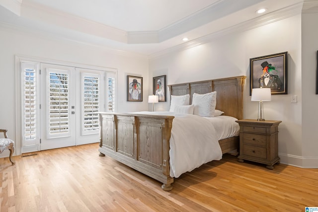 bedroom with access to exterior, a tray ceiling, light wood-style floors, and ornamental molding