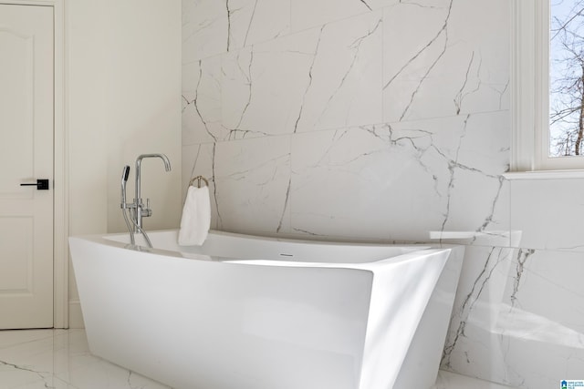 full bath featuring marble finish floor and a freestanding bath