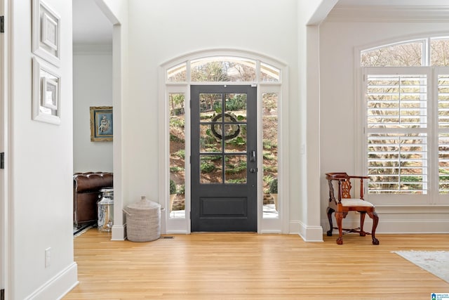 entryway featuring ornamental molding, baseboards, and wood finished floors