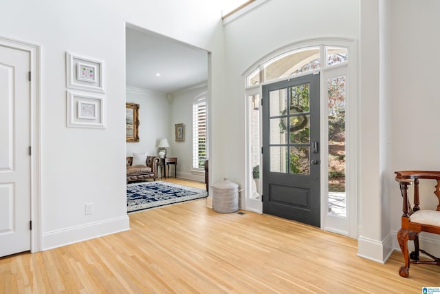 foyer entrance featuring crown molding, wood finished floors, and baseboards