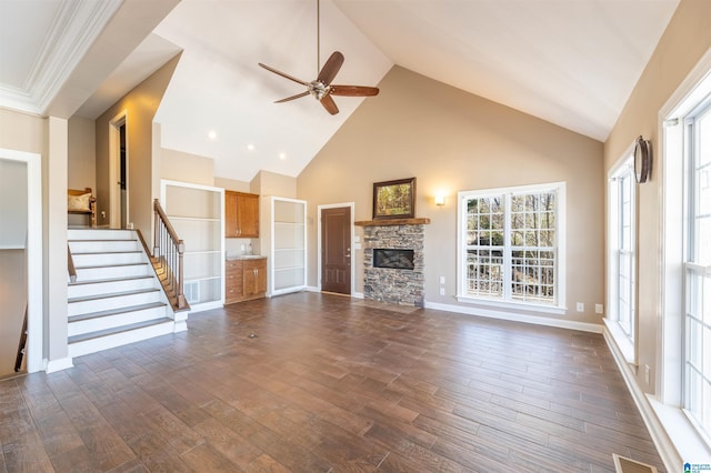 unfurnished living room with dark wood finished floors, a fireplace, ceiling fan, high vaulted ceiling, and stairs