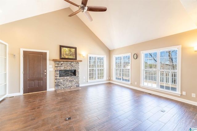 unfurnished living room featuring ceiling fan, high vaulted ceiling, a stone fireplace, dark wood-style flooring, and visible vents