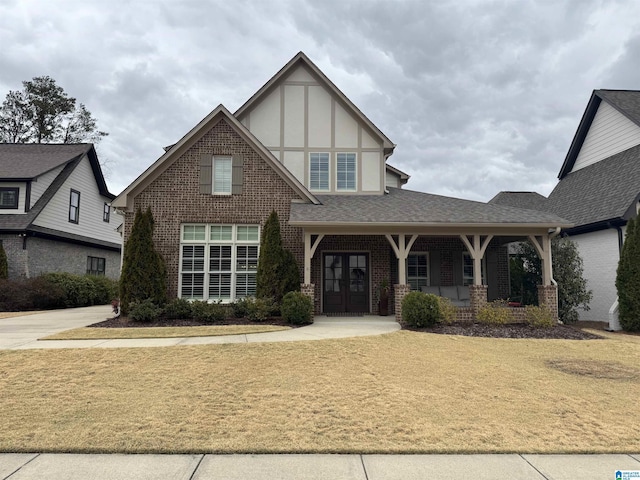 tudor-style house featuring brick siding, stucco siding, and a shingled roof