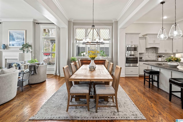 dining room featuring a fireplace, a notable chandelier, dark wood finished floors, and crown molding