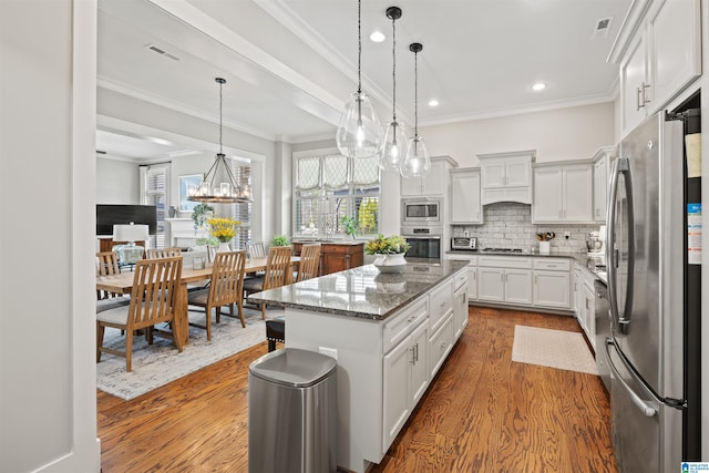 kitchen with visible vents, decorative backsplash, dark wood-type flooring, appliances with stainless steel finishes, and a center island