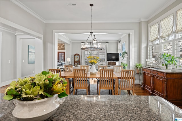 dining space with a notable chandelier, baseboards, crown molding, and visible vents