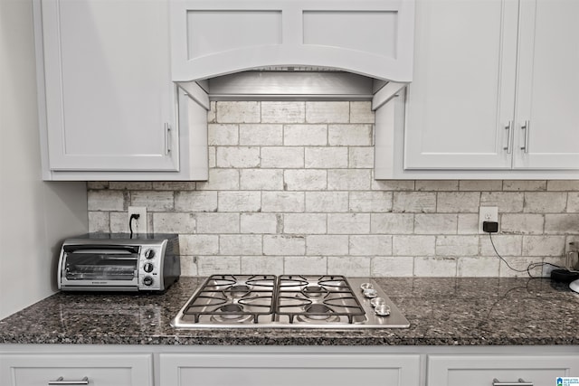 kitchen featuring stainless steel gas cooktop, a toaster, custom range hood, decorative backsplash, and white cabinets