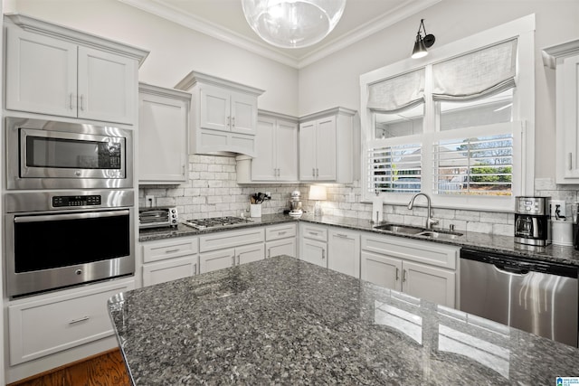 kitchen featuring backsplash, crown molding, stainless steel appliances, white cabinetry, and a sink