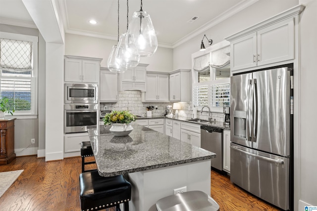 kitchen featuring dark wood finished floors, ornamental molding, a sink, appliances with stainless steel finishes, and tasteful backsplash