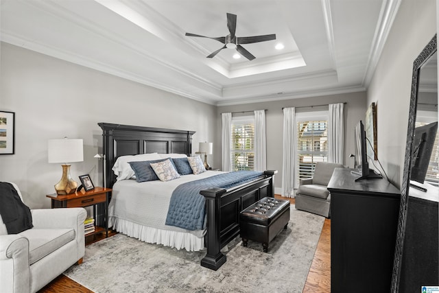 bedroom with a ceiling fan, wood finished floors, a tray ceiling, recessed lighting, and crown molding