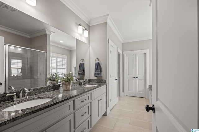 full bathroom with visible vents, double vanity, a sink, a shower stall, and crown molding