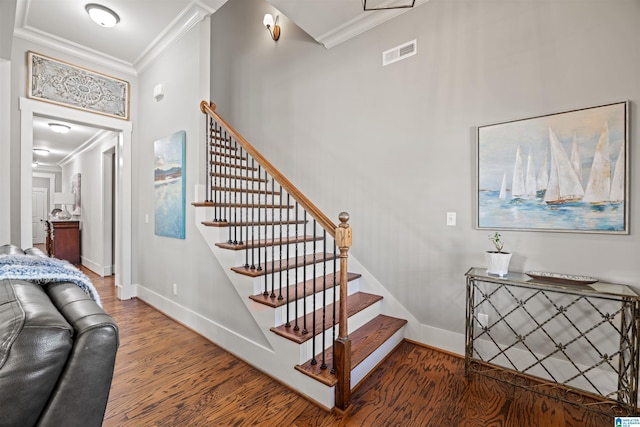 stairway featuring visible vents, wood finished floors, baseboards, and ornamental molding