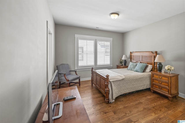 bedroom with visible vents, baseboards, and wood finished floors