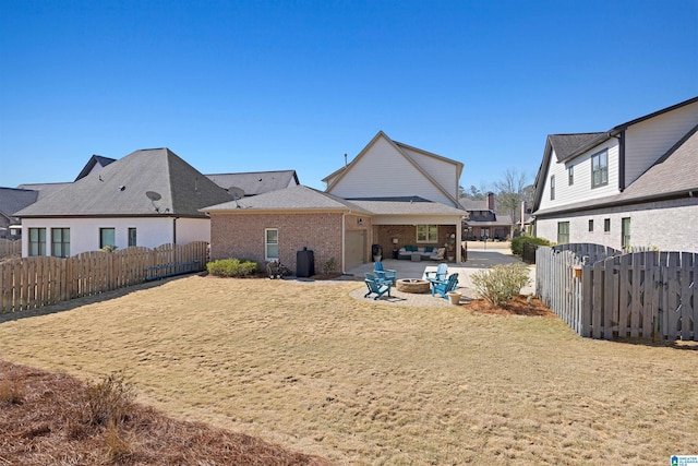 rear view of house with a patio, brick siding, a fenced backyard, and an outdoor fire pit