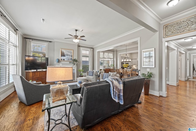 living room with a wealth of natural light, wood finished floors, and ornamental molding