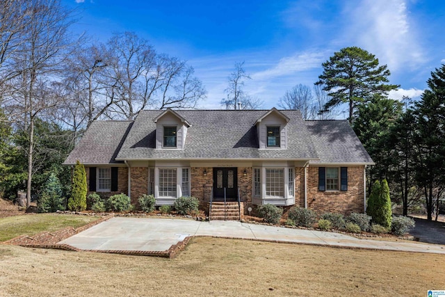 cape cod-style house featuring french doors, roof with shingles, brick siding, and a front lawn