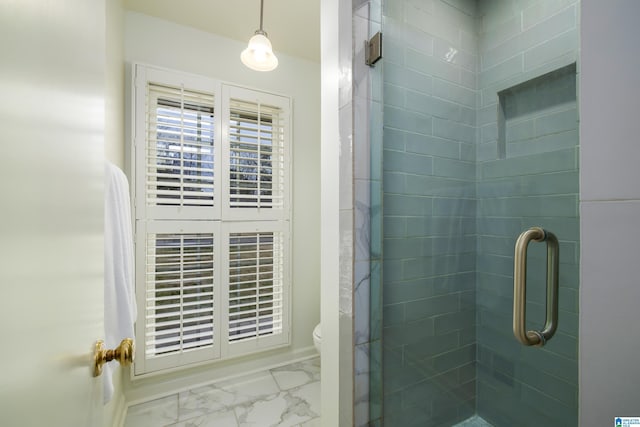 bathroom with toilet, marble finish floor, and a stall shower