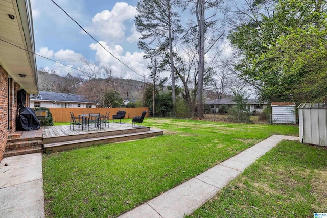 view of yard with a shed, a wooden deck, outdoor dining area, a fenced backyard, and an outdoor structure