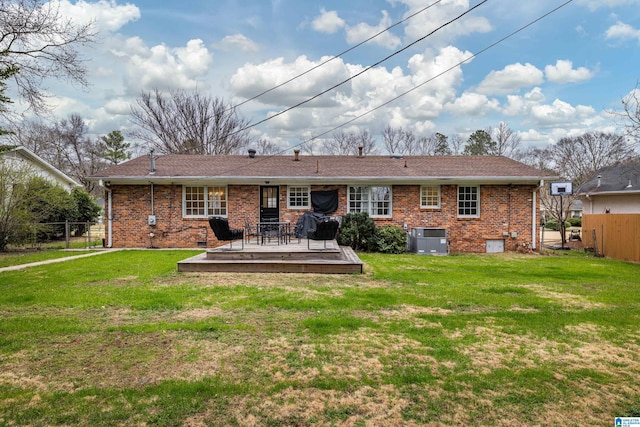 rear view of property with brick siding, a lawn, cooling unit, and fence