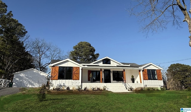 view of front of house featuring an outdoor structure, a porch, and a front yard