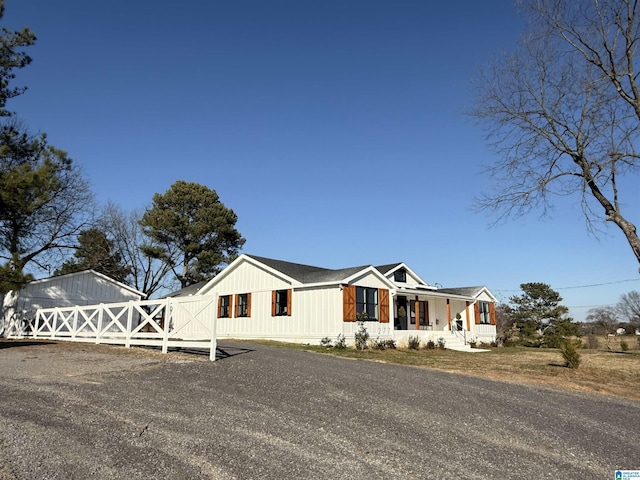 view of front of house with gravel driveway, a gate, fence, and a porch