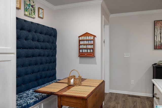 dining room featuring visible vents, baseboards, wood finished floors, and crown molding