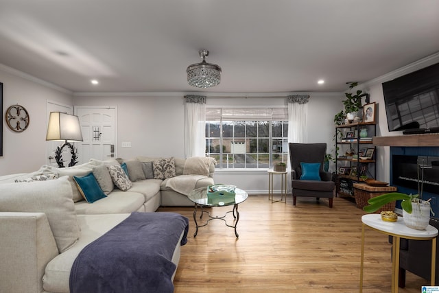 living area with recessed lighting, light wood-type flooring, a large fireplace, and ornamental molding