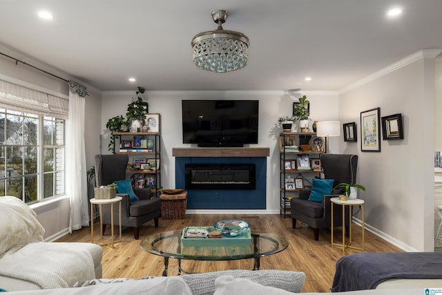 living area with baseboards, ornamental molding, recessed lighting, wood finished floors, and a glass covered fireplace