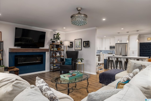 living room featuring crown molding, baseboards, recessed lighting, wood finished floors, and a glass covered fireplace