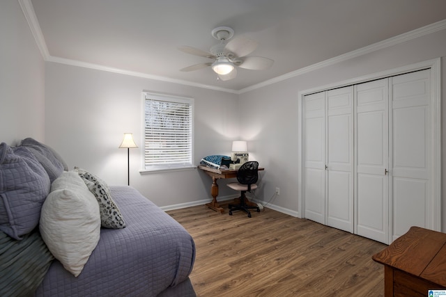 bedroom with wood finished floors, a closet, crown molding, baseboards, and ceiling fan