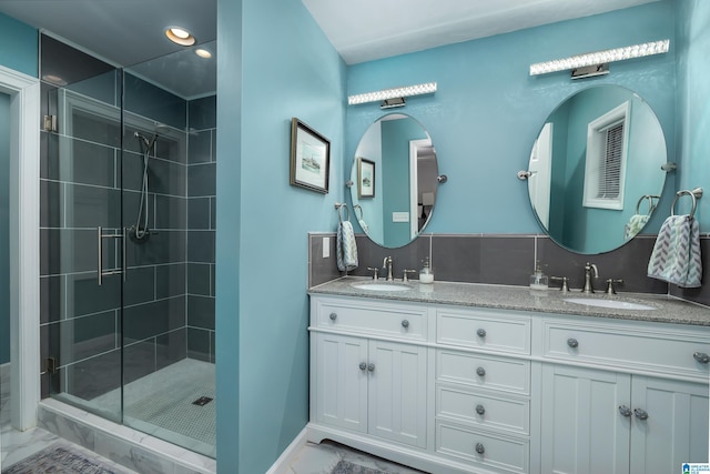 full bath featuring tiled shower, marble finish floor, backsplash, and a sink