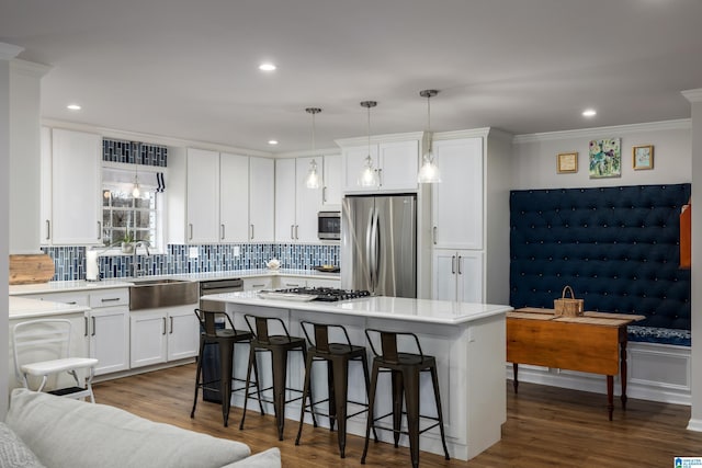 kitchen featuring dark wood-style flooring, light countertops, white cabinets, appliances with stainless steel finishes, and a kitchen bar