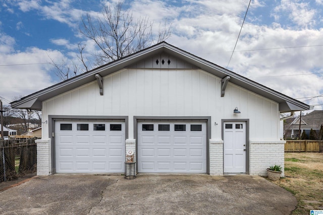 garage featuring driveway and fence