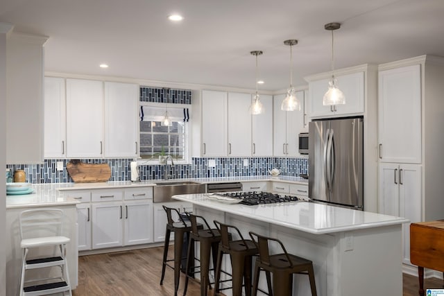 kitchen with a breakfast bar, a sink, stainless steel appliances, light countertops, and white cabinetry