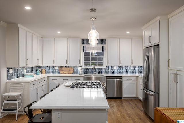 kitchen featuring white cabinetry, appliances with stainless steel finishes, a kitchen island, and wood finished floors