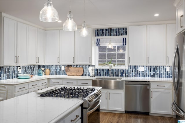 kitchen featuring a sink, dark wood-style floors, white cabinetry, stainless steel appliances, and decorative backsplash