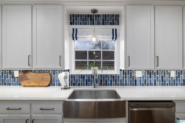 kitchen with stainless steel dishwasher, light countertops, tasteful backsplash, and a sink