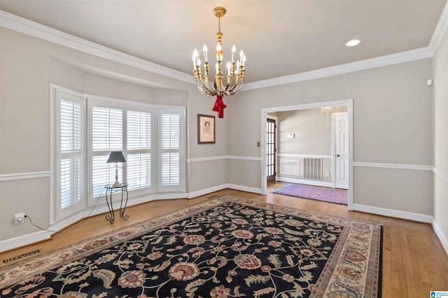 interior space with a notable chandelier, visible vents, crown molding, and wood finished floors