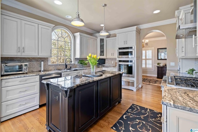 kitchen featuring a toaster, arched walkways, a sink, white cabinets, and appliances with stainless steel finishes