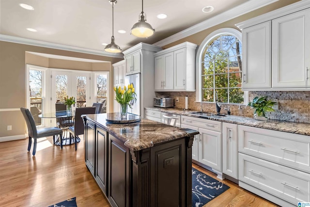 kitchen with tasteful backsplash, ornamental molding, light wood-style floors, refrigerator, and a sink