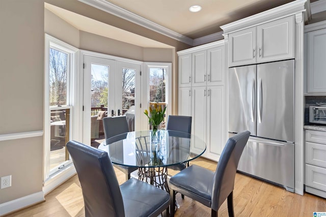 dining space featuring french doors, baseboards, light wood-style floors, and crown molding