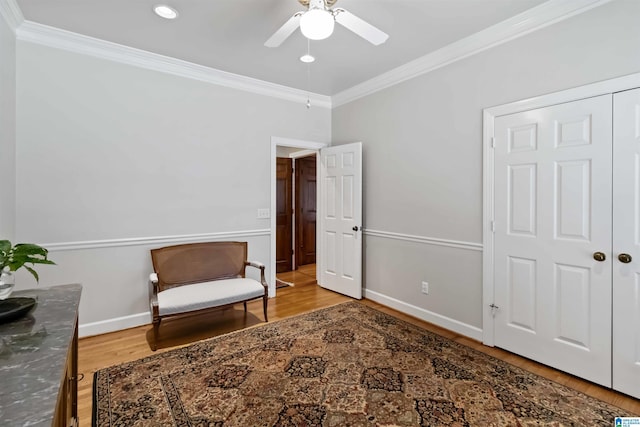 living area featuring crown molding, wood finished floors, baseboards, and ceiling fan