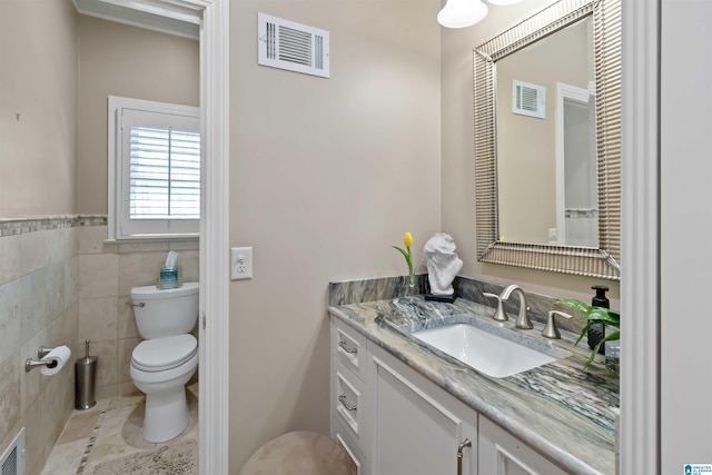 bathroom featuring tile walls, visible vents, toilet, and vanity